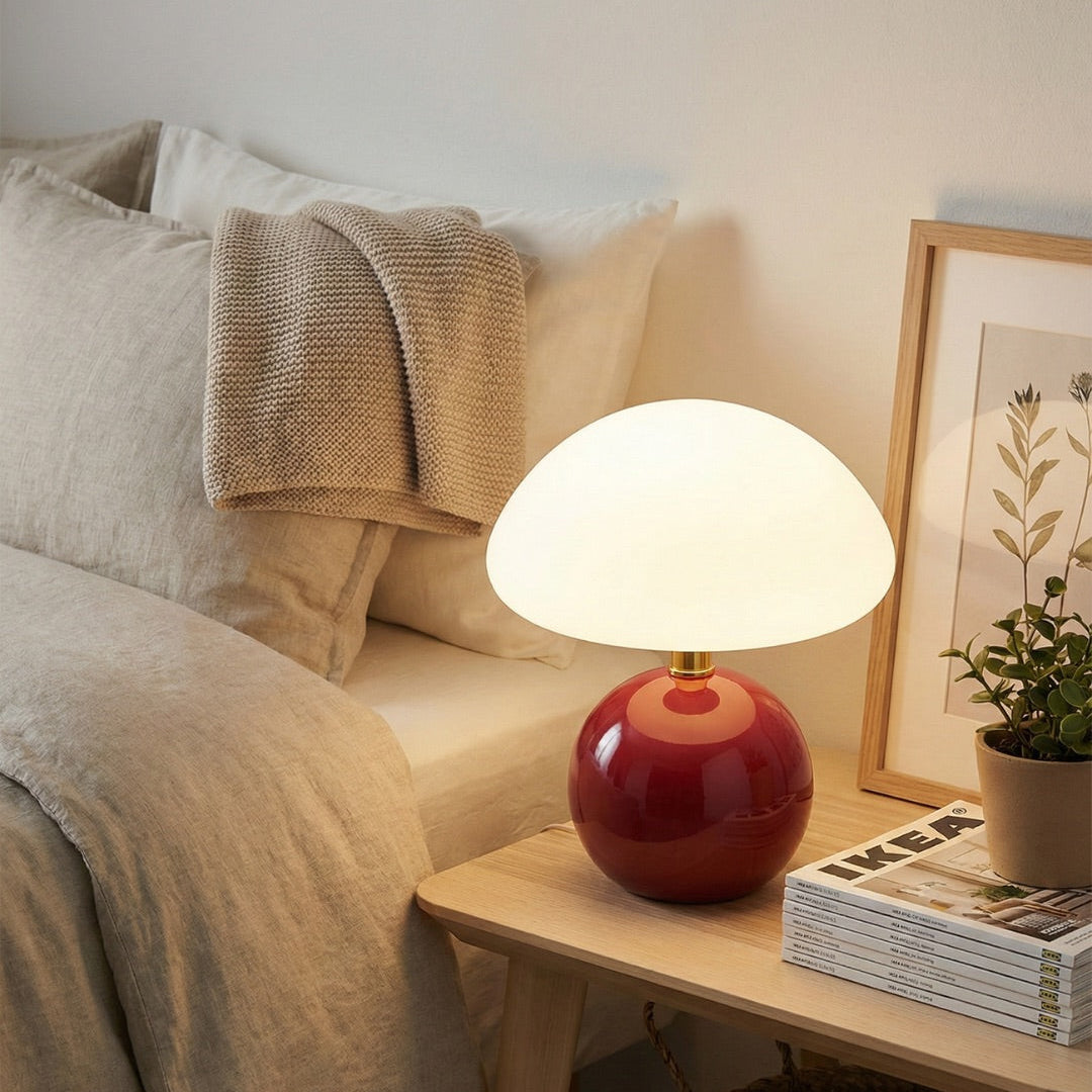 Red table lamp on a wooden surface with magazines